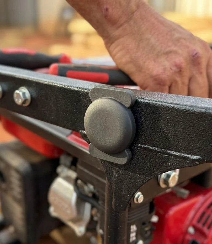 A close-up of a LOKR tracking tag secured inside a dual-tab mounting clip on the black metal frame of a red generator
