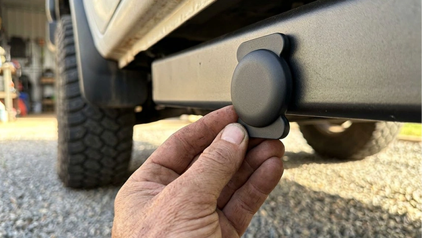 A hand mounting a LOKR tracking tag into a protective, rectangular holder attached beneath a vehicle's chassis