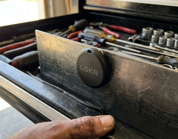 LOKR tracking tag magnetically attached to the metal divider inside an open toolbox drawer filled with hand tools