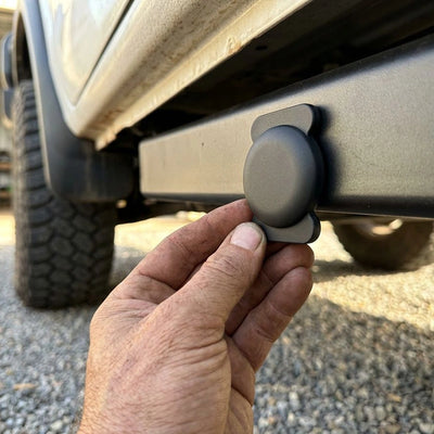 a person placing a LOKR tracking tag with a protective mounting case onto a vehicle's undercarriage bar