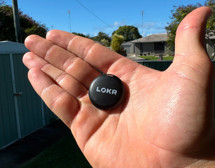 Close-up of a LOKR tracking tag resting in the palm of an open hand